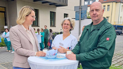 Geschäftsführerin Verena Plocher unterhält sich an einem Tisch mit zwei Mitarbeitenden auf dem Außengelände des Immanuel Klinikums Bernau Herzzentrum Brandenburg am Internationalen Tag der Pflegenden.
