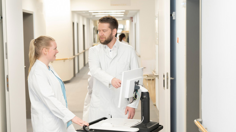 Prof. Dr. med. Torsten Diekhoff spricht mit einer Medizinstudentin an einem mobilen Visitenwagen auf dem Flur - Immanuel Klinik Rüdersdorf - Nachricht - Weiterbildungsbefugnisse stärken ärztlichen Nachwuchs in Rüdersdorf Prof. Dr. med. Torsten Diekhoff spricht mit einer Medizinstudentin an einem mobilen Visitenwagen auf dem Flur - Immanuel Klinik Rüdersdorf - Nachricht - Weiterbildungsbefugnisse stärken ärztlichen Nachwuchs in Rüdersdorf