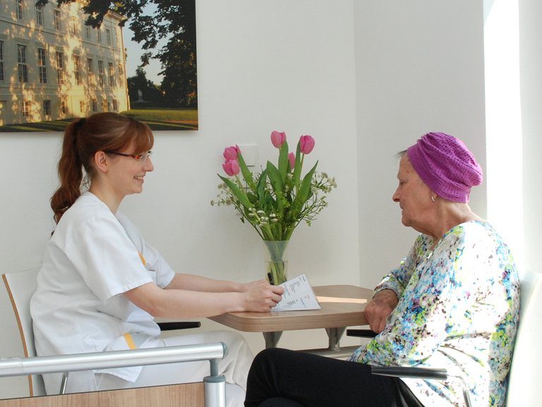Pflegerin mit Patientin an einem Tisch - Immanuel Klinik Rüdersdorf bei Berlin - Palliativmedizin