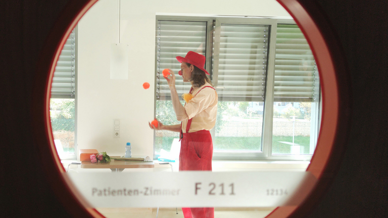 Sicht auf Clown in Patientenzimmer durch Bullauge - Immanuel Klinik Rüdersdorf bei Berlin - Clown-Visite