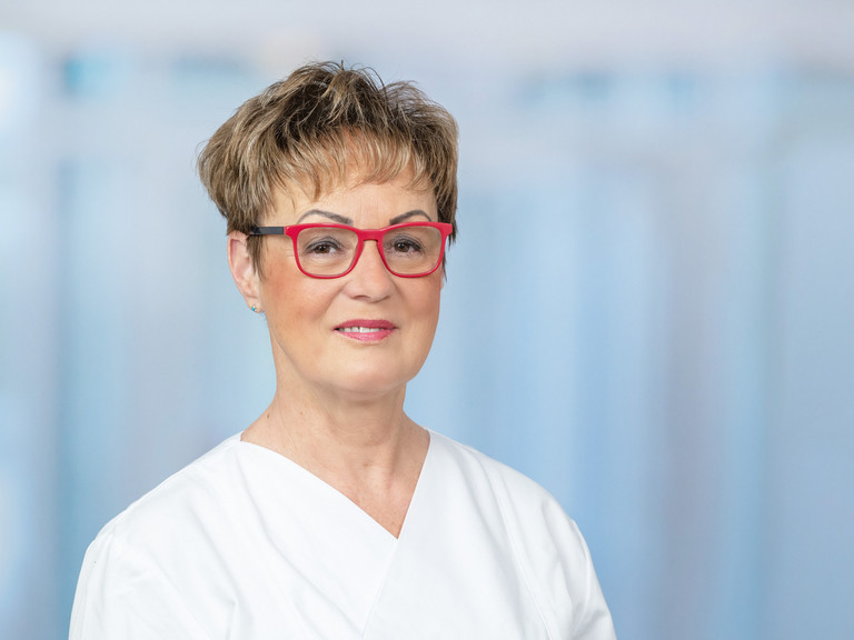 Portraitfoto vor grau-blauem Hintergrund von Marion Baldy, Leitende Hygienefachkraft für die Krankenhäuser und Pflegeeinrichtungen der Immanuel Albertinen Diakonie in Berlin und Brandenburg