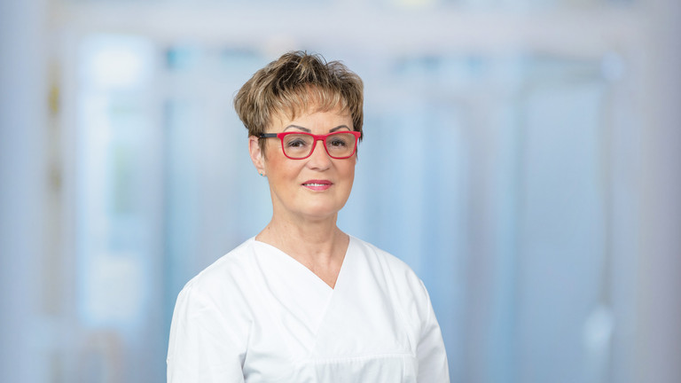 Portraitfoto vor grau-blauem Hintergrund von Marion Baldy, Leitende Hygienefachkraft für die Krankenhäuser und Pflegeeinrichtungen der Immanuel Albertinen Diakonie in Berlin und Brandenburg