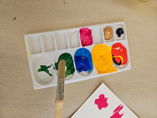 Eine Farbpalette mit mehreren bunten Farben und Pinsel aus der Kunsttherapie in der Immanuel Klinik Rüdersdorf