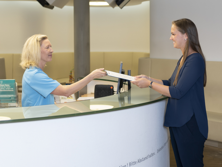 Mitarbeiterin überreicht Unterlagen an Patientin - Immanuel Klinik Rüdersdorf - Palliativmedizin - Kontakt und Anmeldung