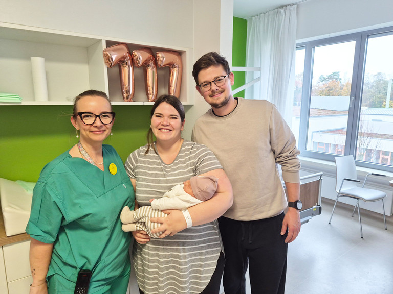 Hebamme mit Mutter, die das Baby im Arm hält und Vater in der Immanuel Klinik Rüdersdorf