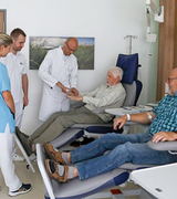 Zwei ältere Patienten sitzen auf Medizinischen Stühlen und führen ein Gespräch mit Ärzten, Tagesklinik Neurologie und Schmerztherapie, Immanuel Klinik Rüdersdorf, Rüdersdorf bei Berlin